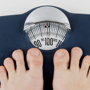 Barfuß auf einer Waage, die fast hundert Kilo anzeigt.