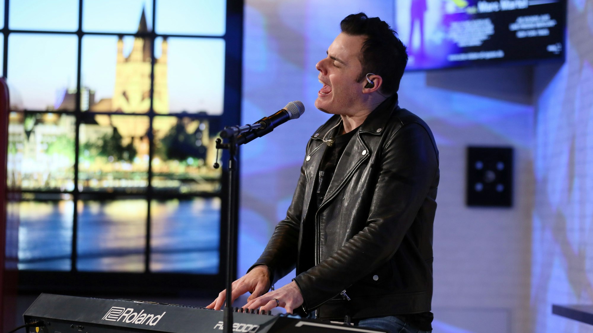 Mann in Lederjacke singt und spielt auf einem Keyboard.