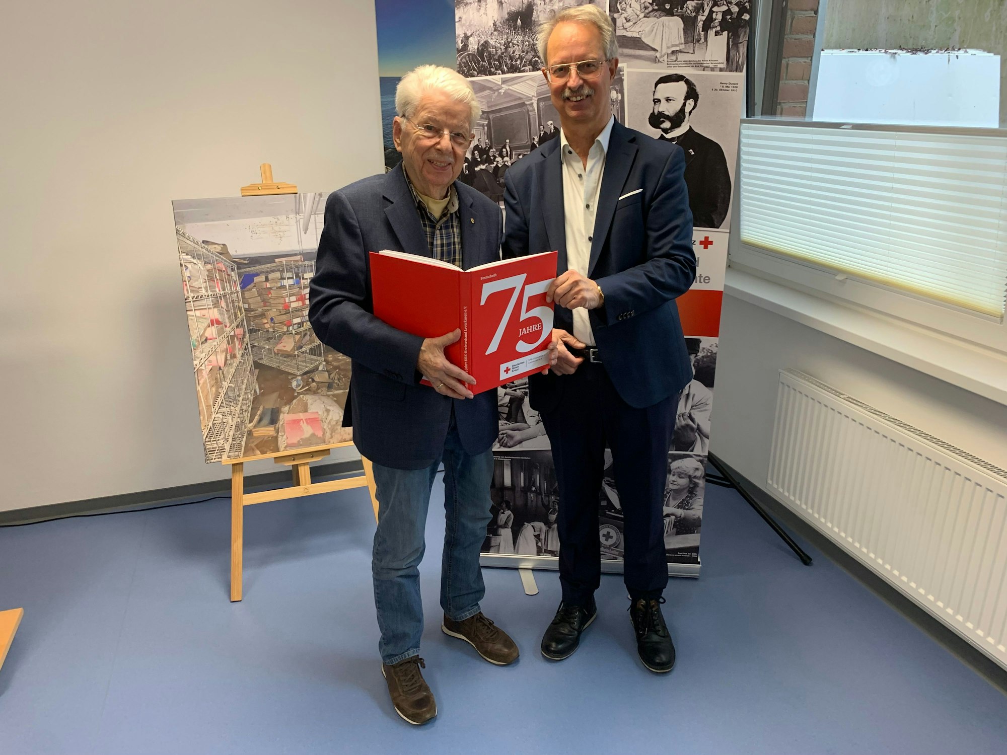 Toni Blankerts (v.l., ehemaliger Kreisgeschäftsführer und Heimleiter des DRK-Kreisverbandes) und sein Nachfolger Josef Peters präsentieren stolz die Chronik zum 75-jährigen Bestehen ihres Kreisverbandes.