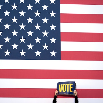 Ein Unterstützer hält ein Schild hoch, mit der Aufforderung zu Wählen.