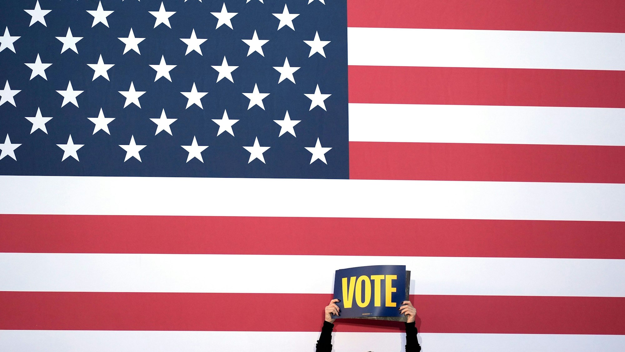 Ein Unterstützer hält ein Schild hoch, mit der Aufforderung zu Wählen.