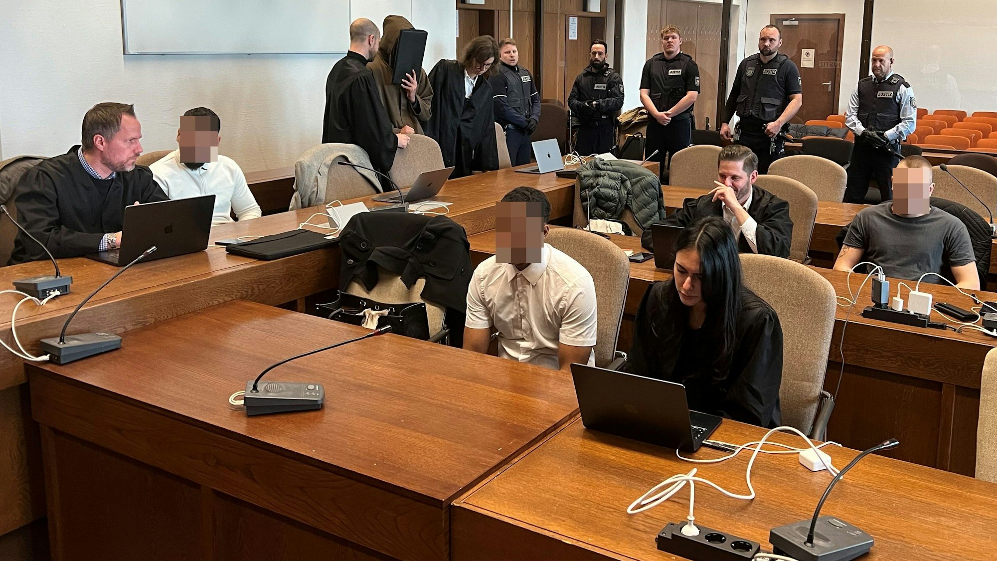 Die vier Angeklagten mit ihren Verteidigern beim Prozessauftakt im Kölner Landgericht