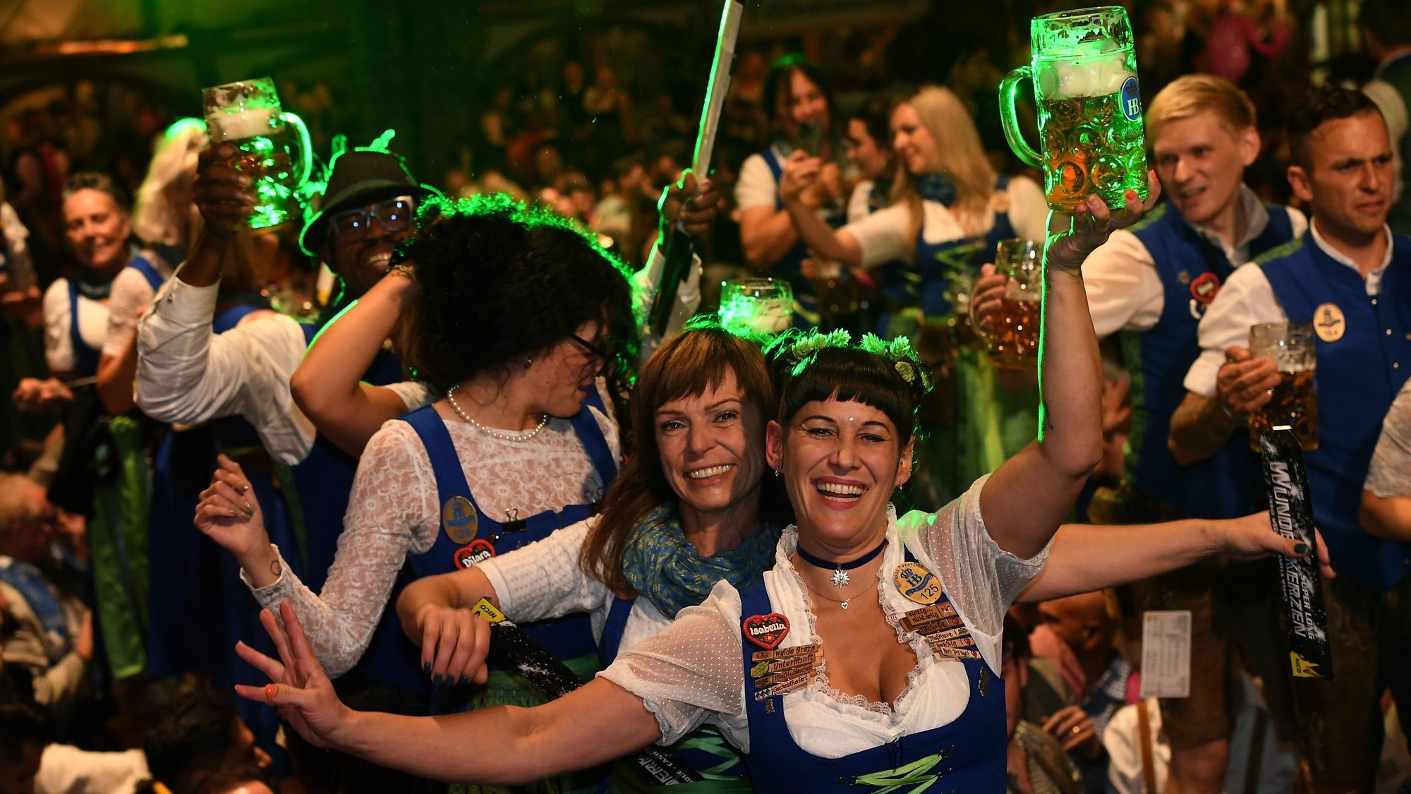 Feiernde Menschen in Dirndl und Lederhosen und mit Bierkrügen