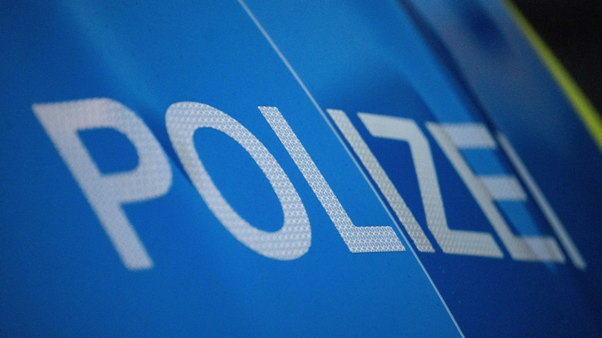 Das Foto zeigt einen Polizei-Schriftzug auf einem Einsatzwagen.