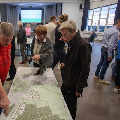 Zwei Frauen und ein Mann beugen sich über eine Karte.
