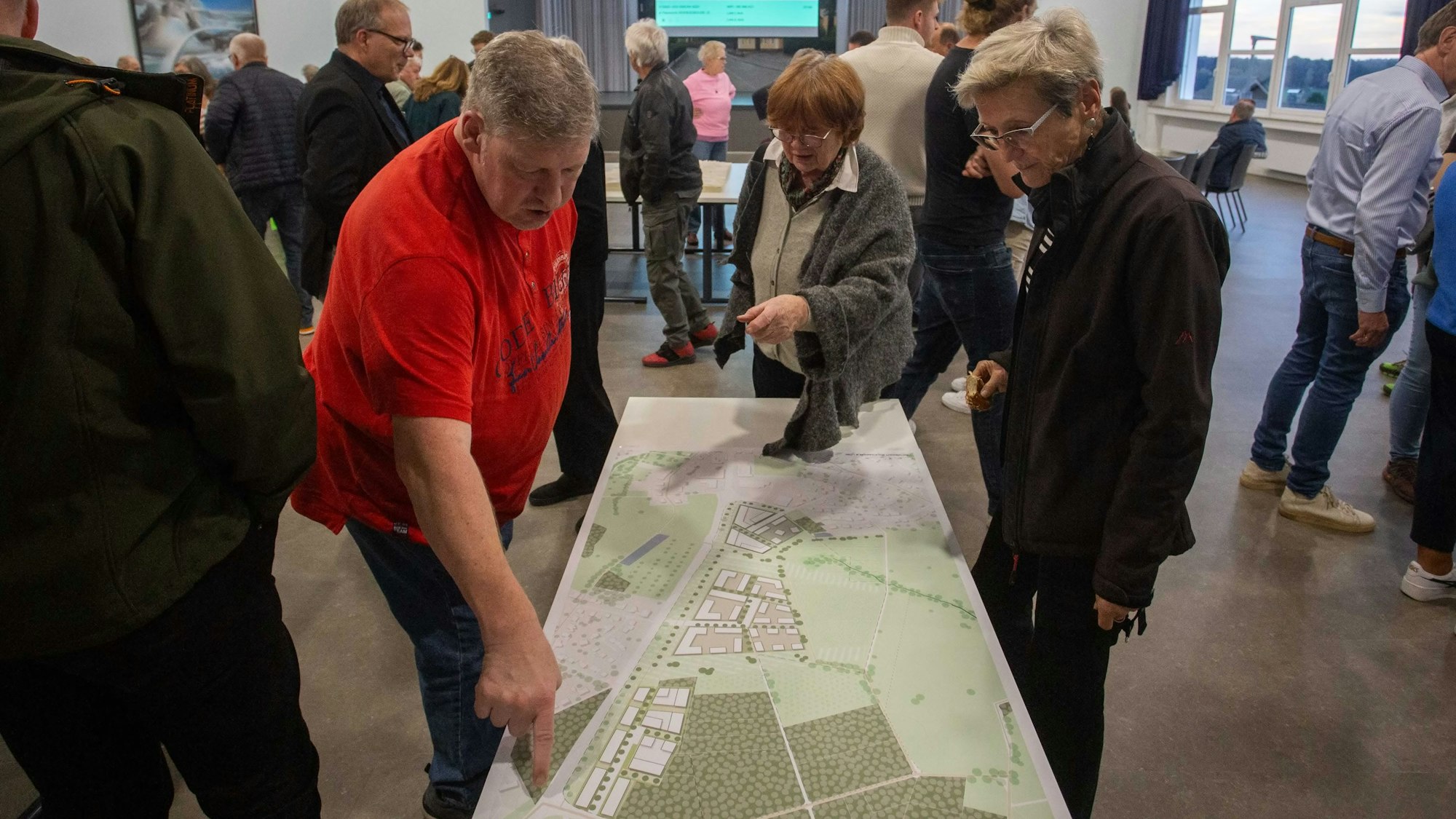Zwei Frauen und ein Mann beugen sich über eine Karte.