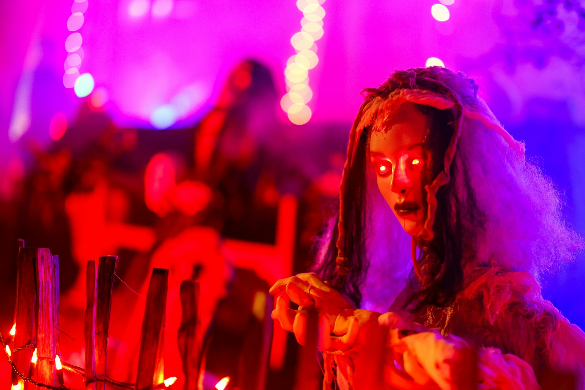 Mettmann: An einem Zaun wartet eine gruselige Figur mit rot leuchtenden Augen auf die Besucher im Halloween-Grusel-Haus in Mettmann.