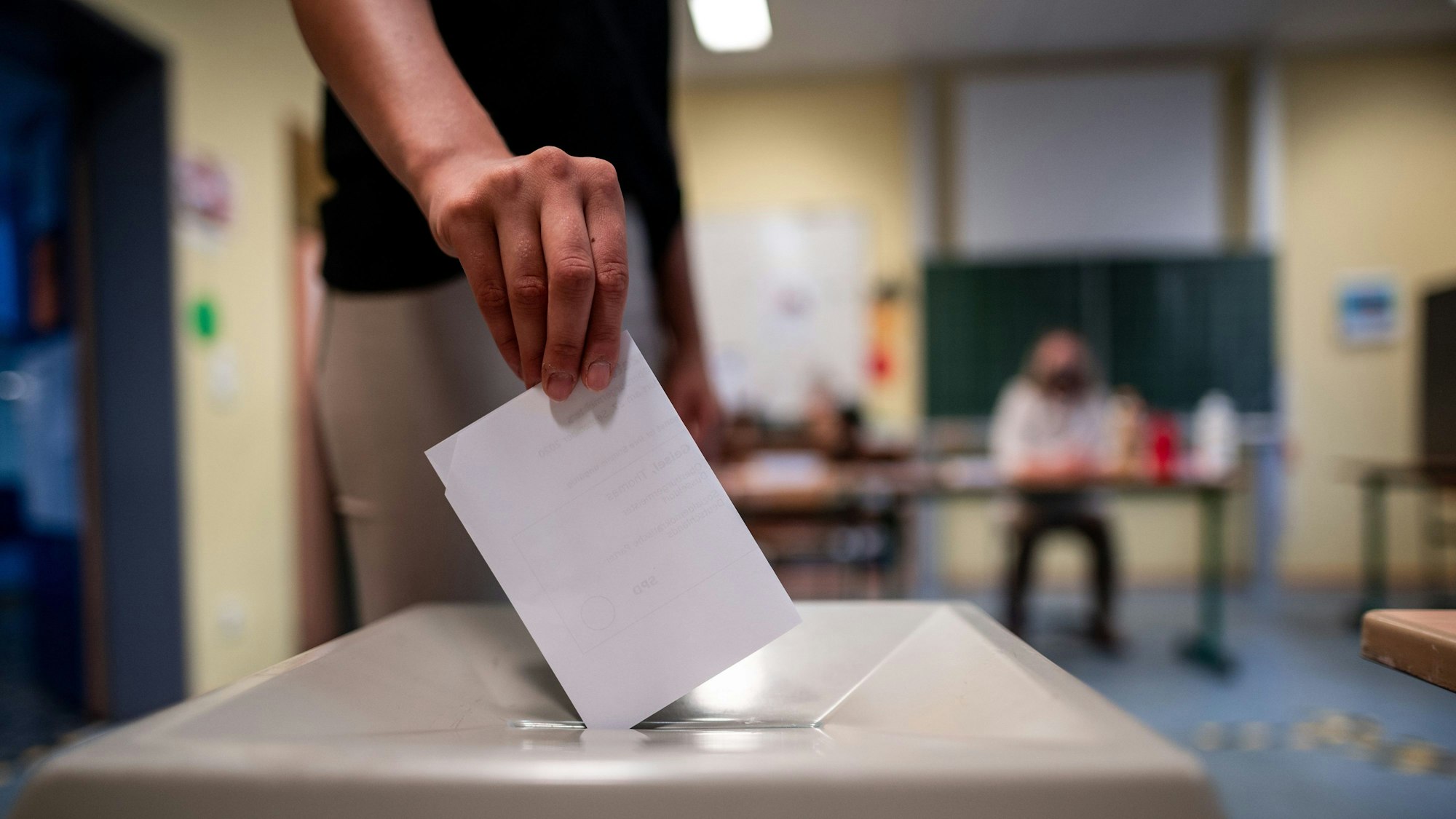 Eine Frau wirft einen Wahlschein in eine Wahlurne.