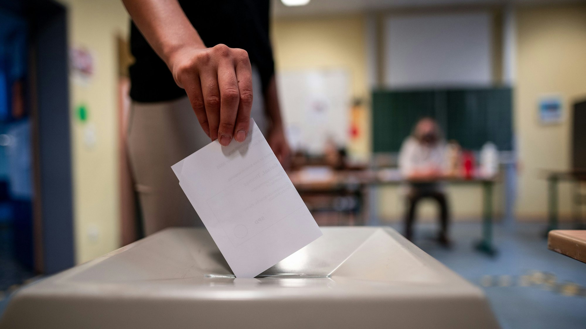 Eine Frau wirft einen Wahlschein in eine Wahlurne.