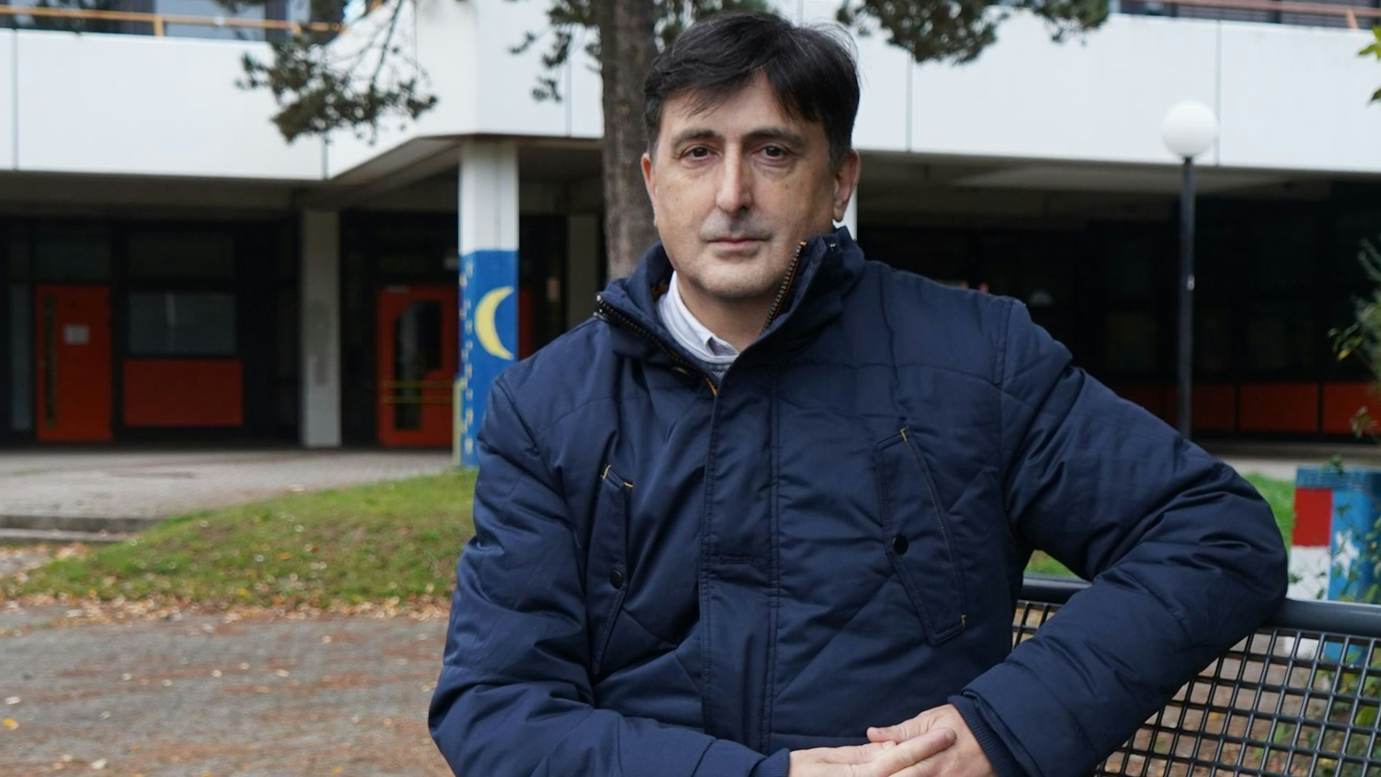 Auf dem Foto ist ein Mann zu sehen, der auf einer Bank sitzt.