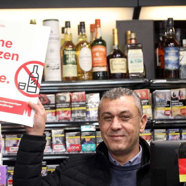 Verkäufer Kenan Aslan zeigt in einem Kiosk an der Marzellenstraße ein Plakat mit dem bekannten Motto „Keine Kurze für Kurze“'.