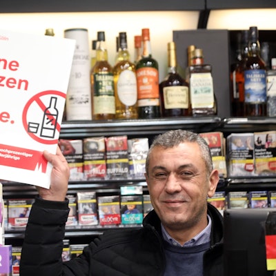 Verkäufer Kenan Aslan zeigt in einem Kiosk an der Marzellenstraße ein Plakat mit dem bekannten Motto „Keine Kurze für Kurze“'.