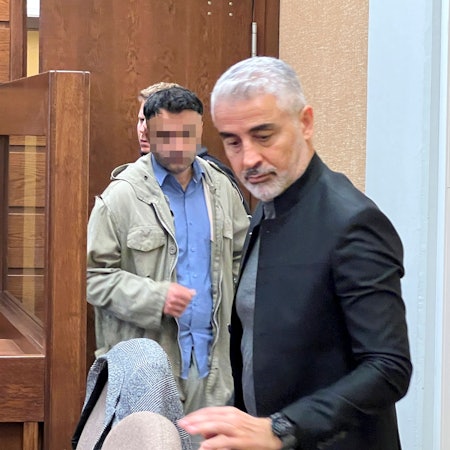 Landgericht Köln: Ein Mann soll einen anderen in Rheindorf mit fast 26 Messerstichen getötet haben. Hier wird er aus dem Keller in den Gerichtssaal geführt. Im Vordergrund: Verteidiger Mustafa Kaplan.