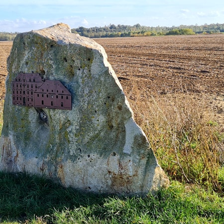 Das Abbild des Klosters ist auf einem großen Fels angebracht, der vor einem Feld steht.
