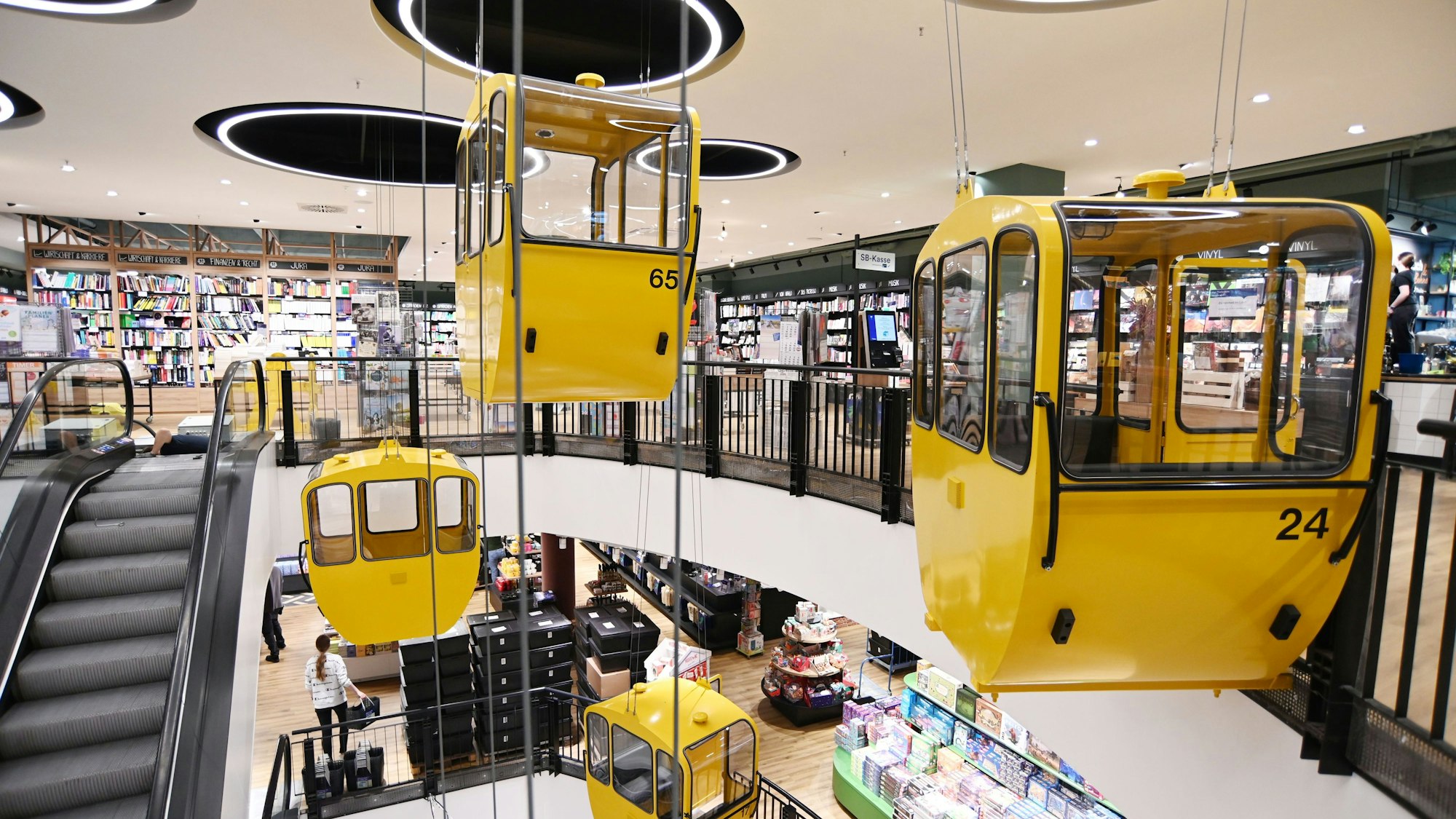 Gondeln, die an die Rheinseilbahn erinnern, schweben nun im Treppenhaus der Thalia Mayerschen.