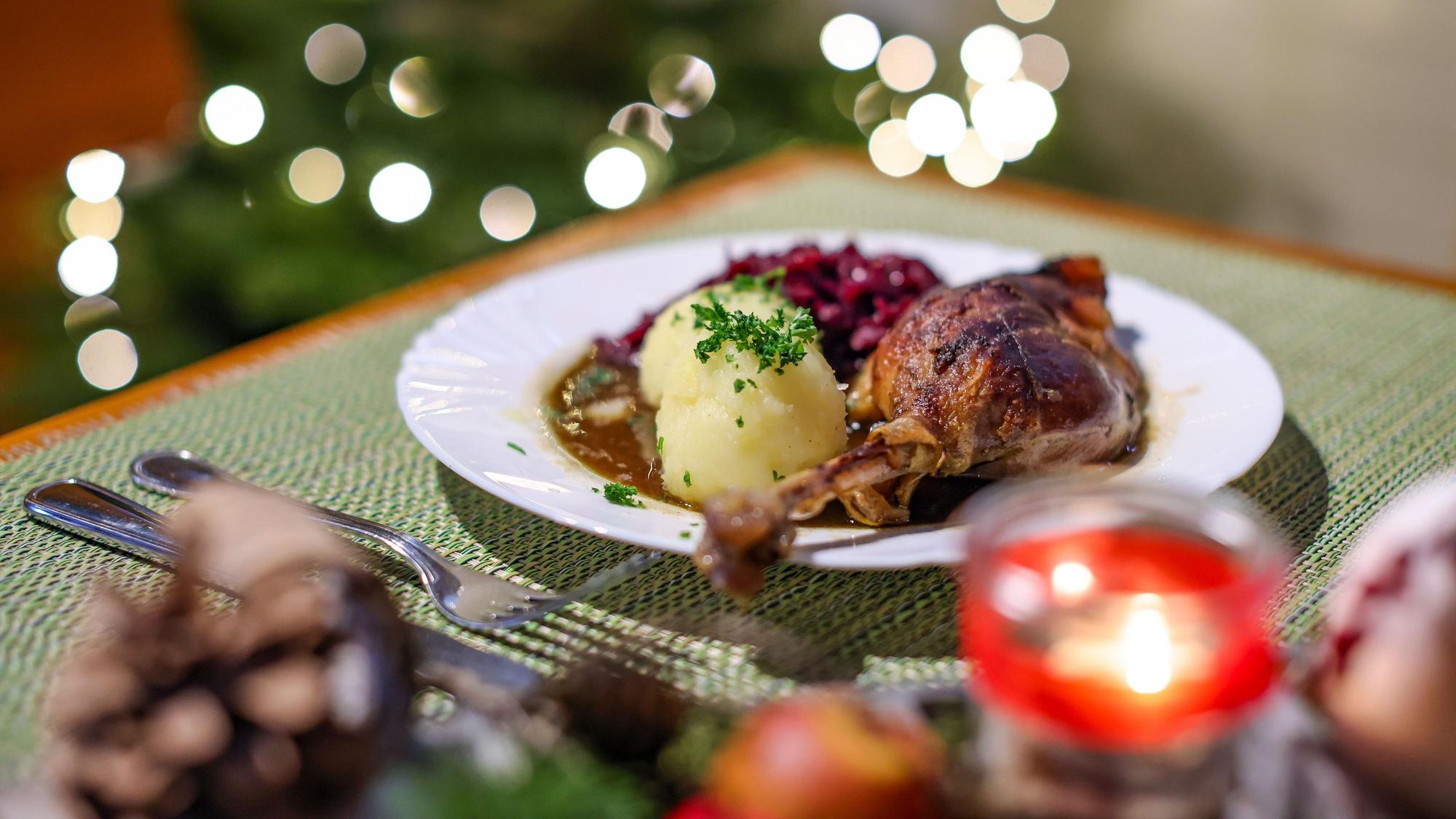 Eine Portion Gänsekeule mit Rotkraut und Klößen steht auf einem Tisch in einem Restaurant.