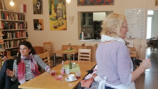 Eine Frau sitzt im Café an einem Tisch, sie unterhält sich.