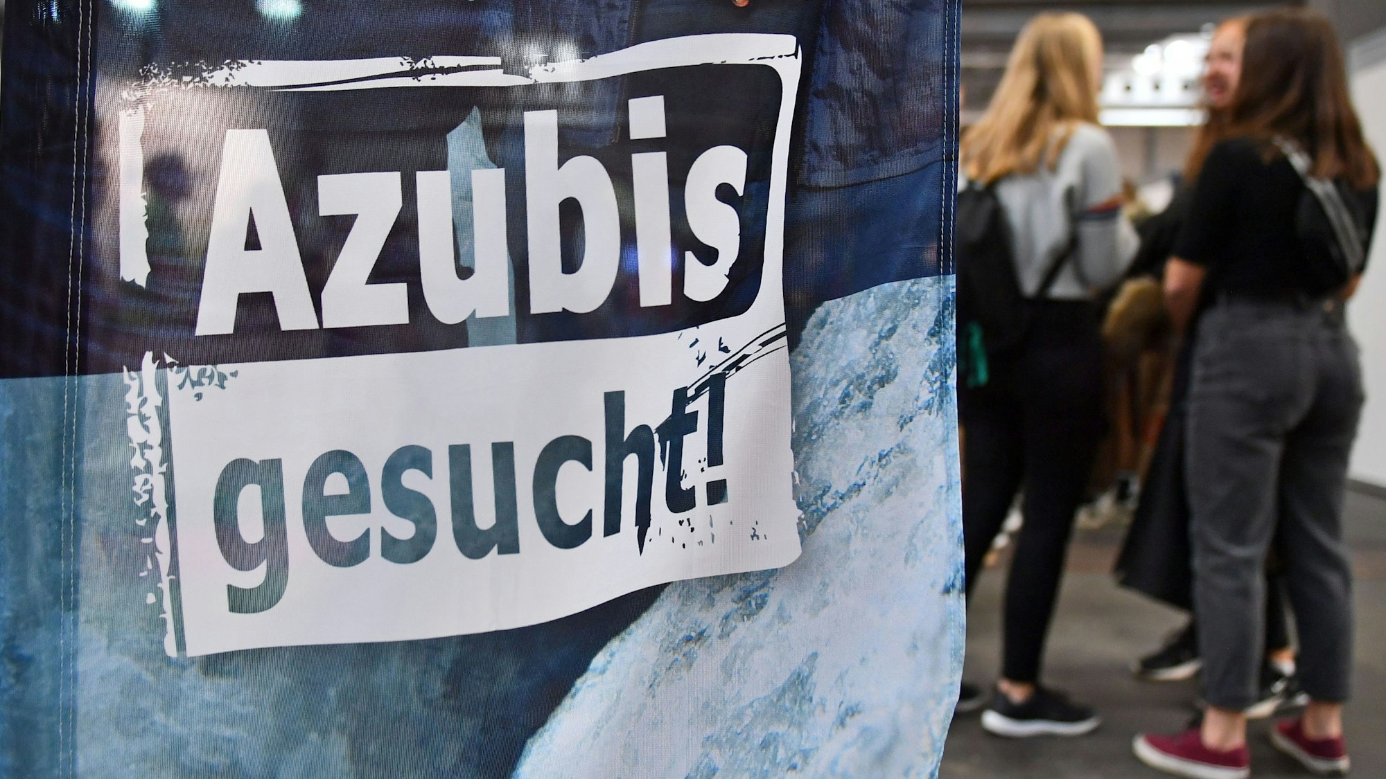 Auf einem Banner bei einer Berufsorientierungsmesse steht „Azubis gesucht“.