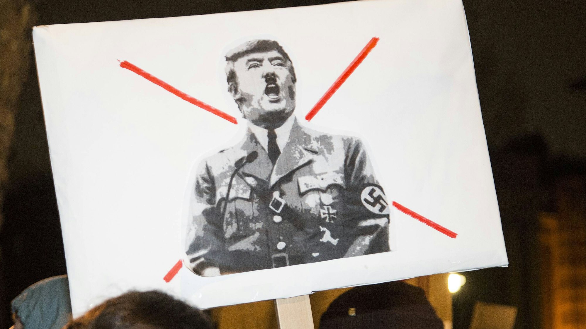 Ein Demonstrant trägt bei einem Protest ein Schild, auf dem Donald Trump in Nazi-Uniform und mit Hitler-Bart abgebildet ist. (Archivbild)
