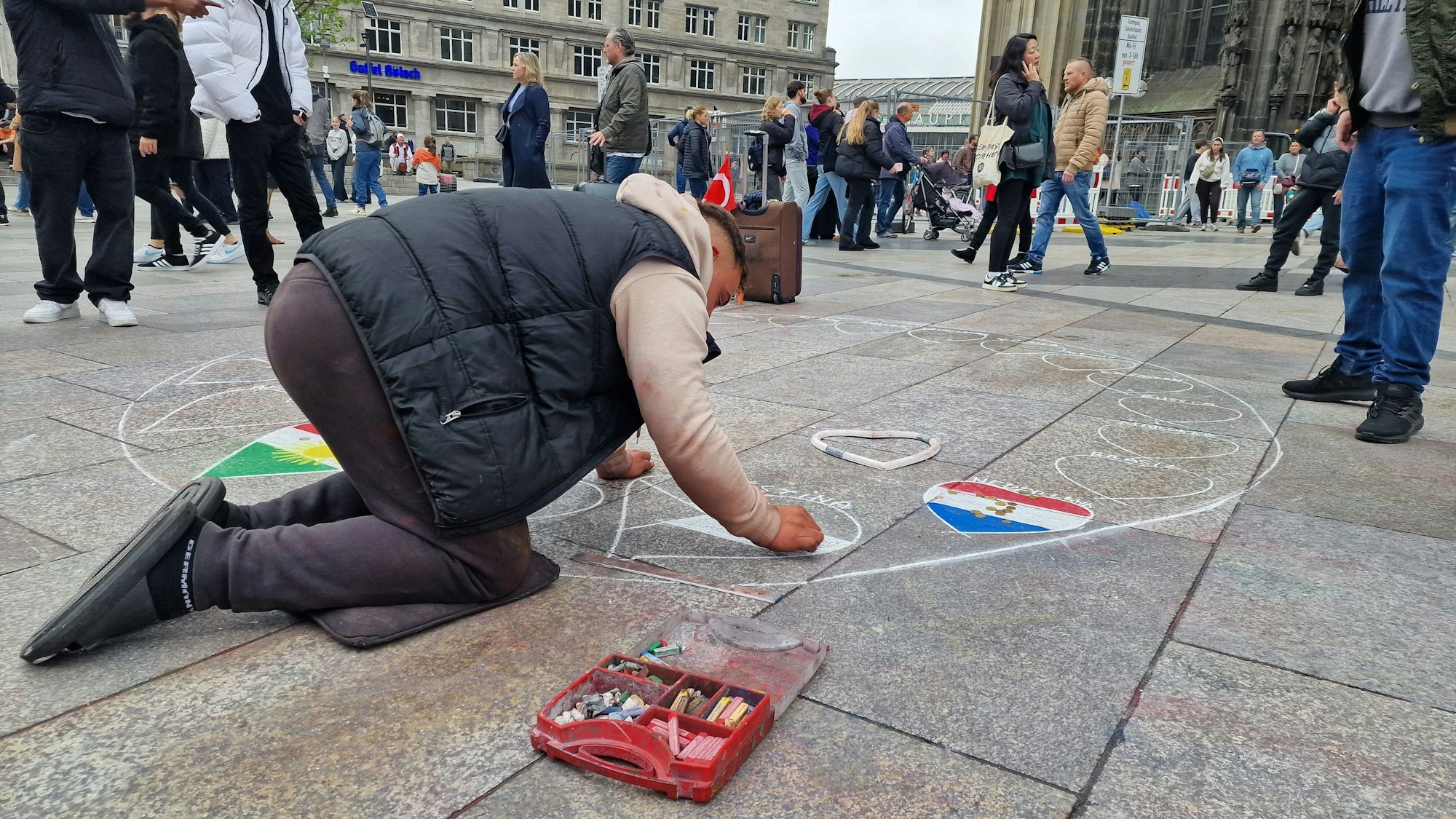 Ein Straßenmaler auf der Domplatte malt am Mittwoch Länderflaggen. Zu dem geplanten Verbot wollte er sich nicht äußern.