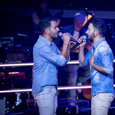 Zwei Brüder singen auf einer Bühne.