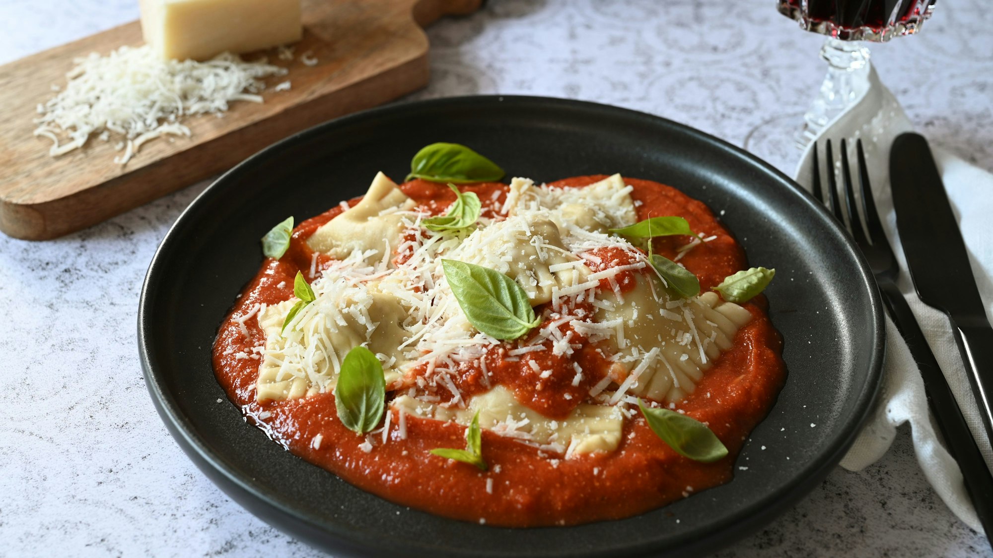 Die selbstgemachten Ravioli thronen beim Servieren auf der Tomatensoße. Basilikumblätter sorgen für einen Farbtupfer.