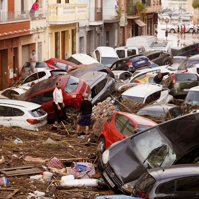 30.10.2024, Spanien, Valencia: Anwohner betrachten durch die Wassermassen aufgestapelte Autos. Foto: Alberto Saiz/AP +++ dpa-Bildfunk +++
