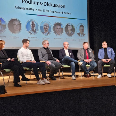 Die Teilnehmer einer Podiumsdiskussion der DLG Eifel sitzen auf der Bühne des Gemünder Kurhauses.