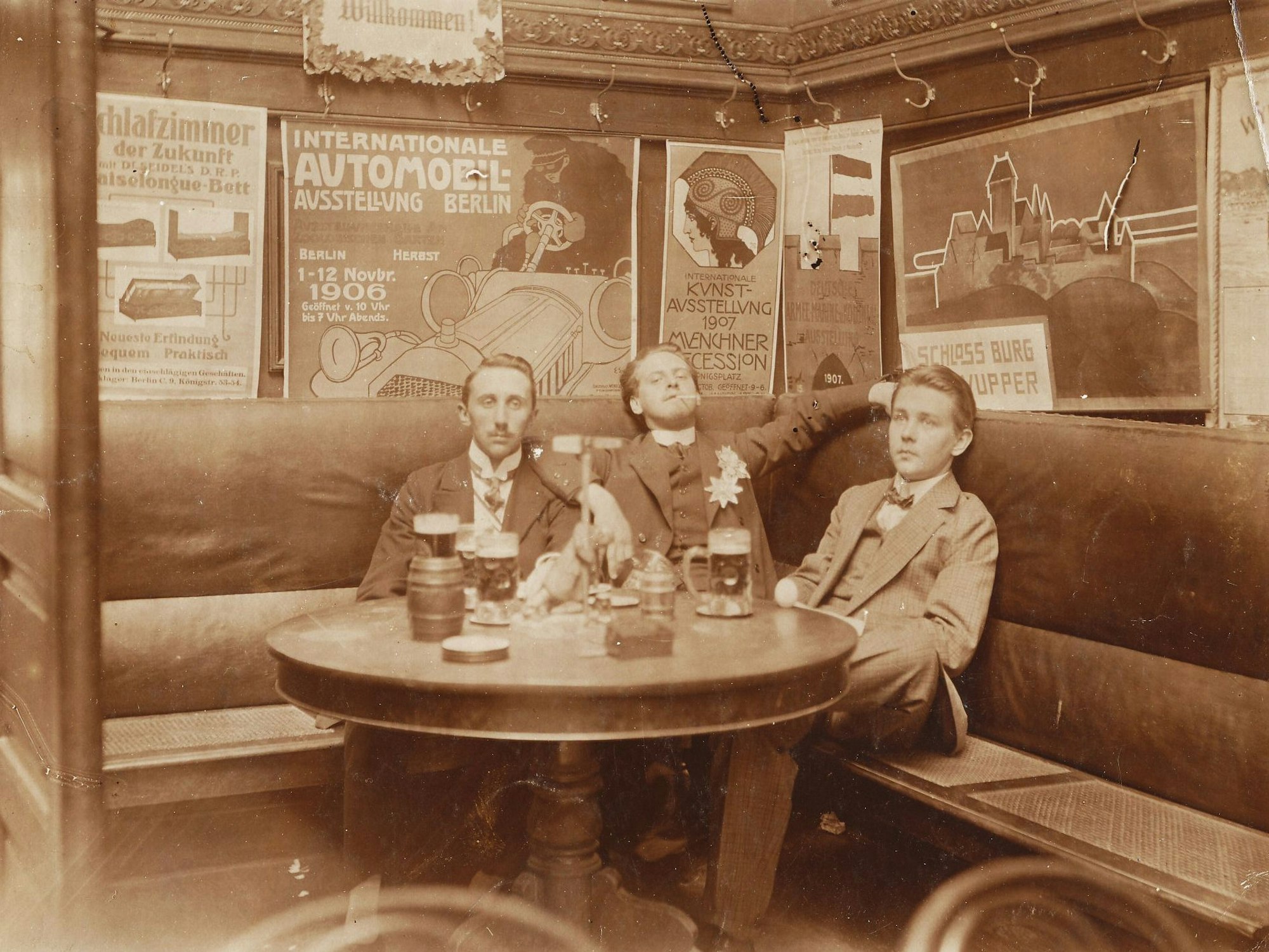 Drei Männer sitzen in einer Kneipe an einem Tisch.