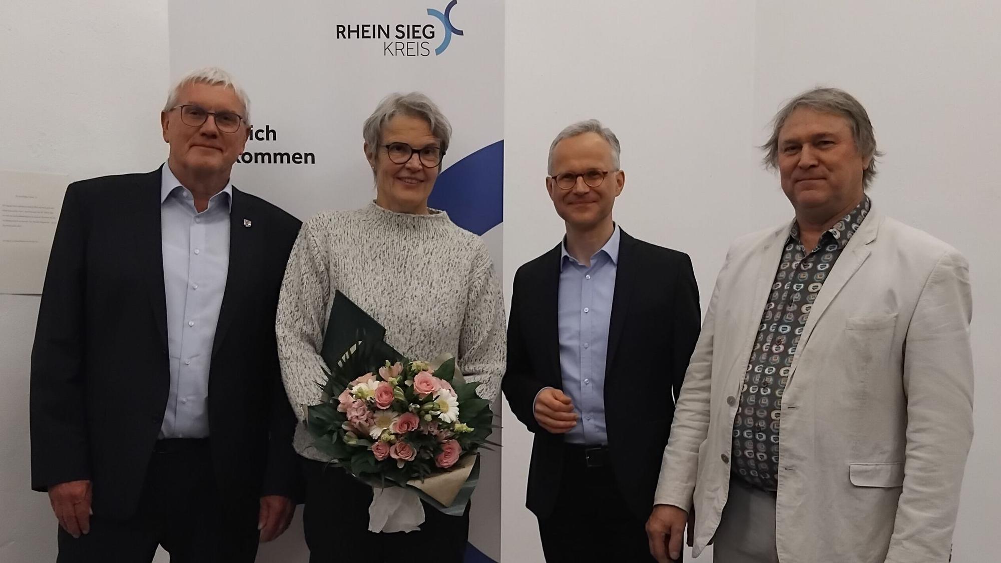 Drei Männer und eine Frau mit Blumenstrauß.