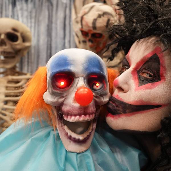 Die geschminkte und verkleidete Mitarbeiterin Simone Rumke küsst eine Grusel-Clownsfigur mit leuchtenden Augen.