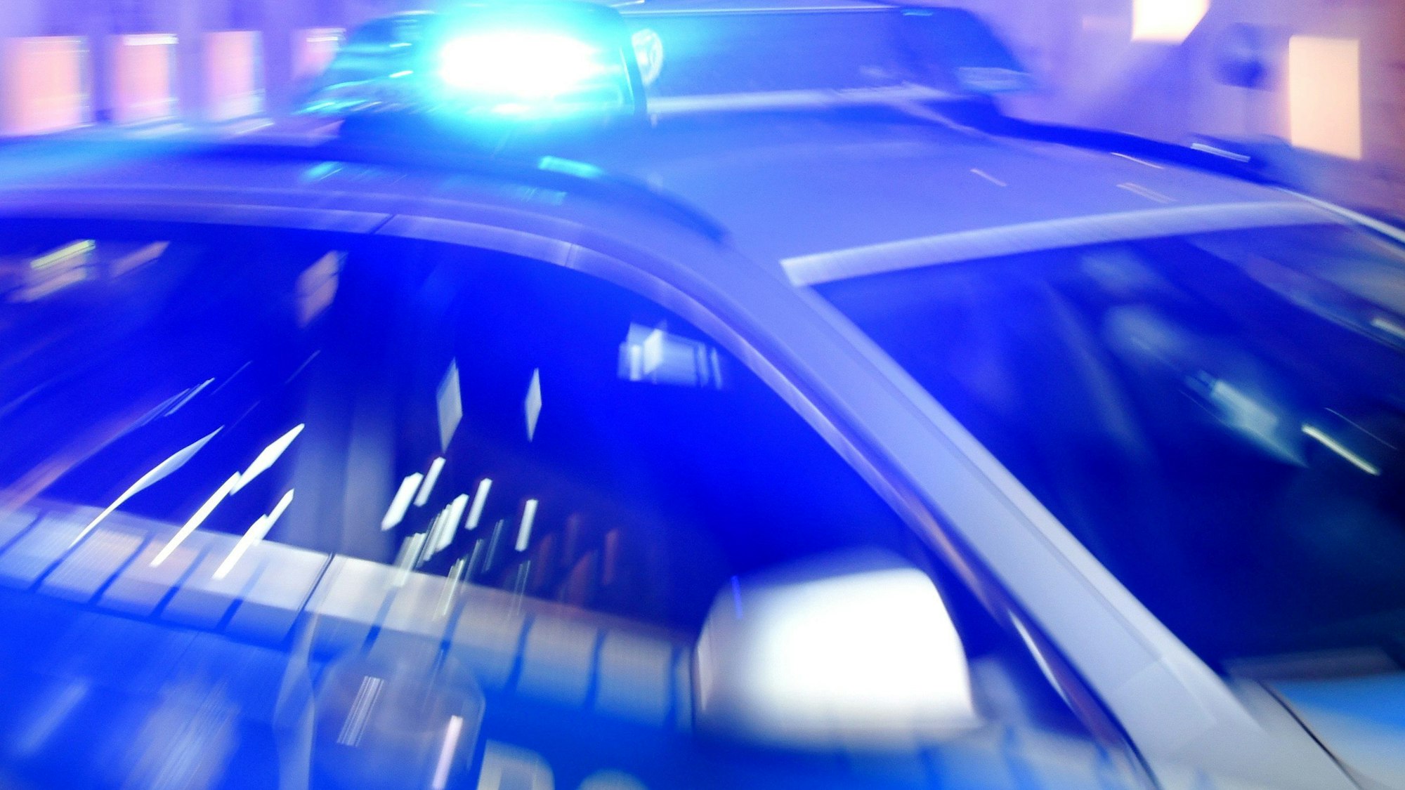 Ein Streifenwagen der Polizei steht mit eingeschaltetem Blaulicht auf der Straße.