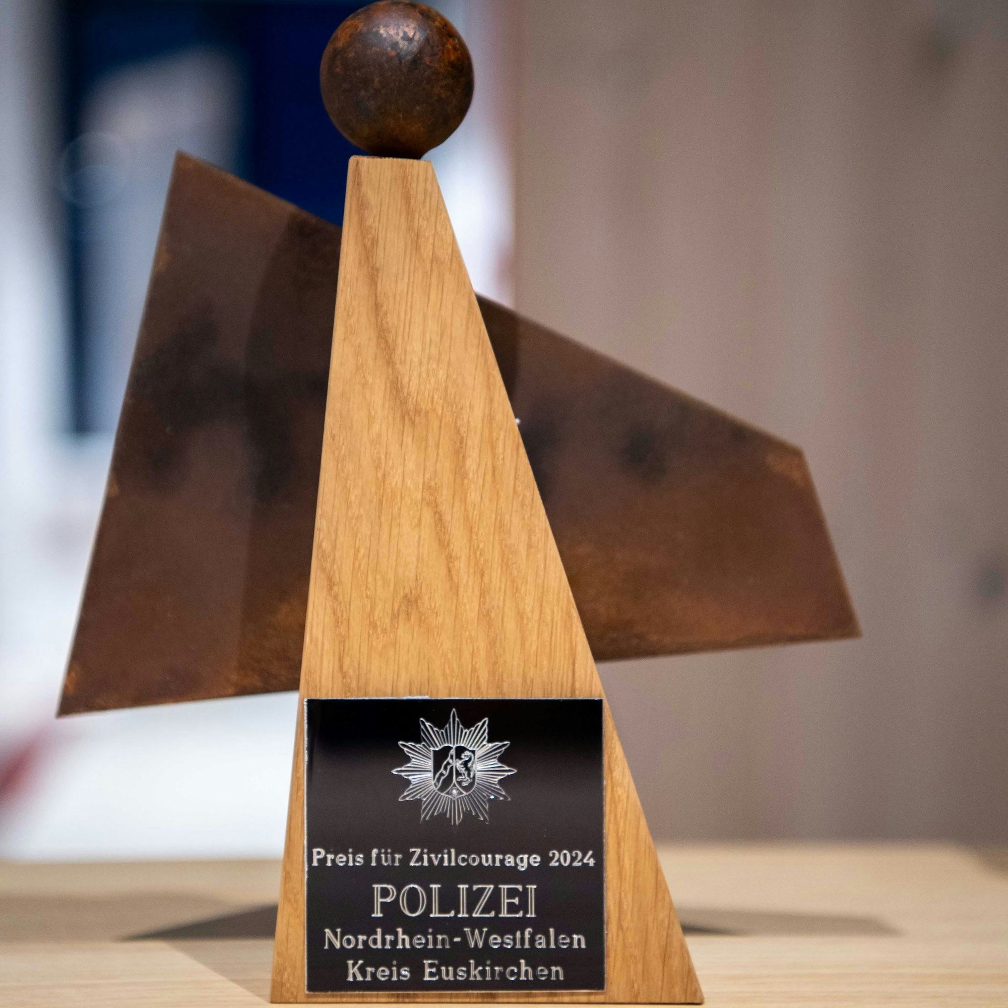 Das Bild zeigt einen kleinen Preis aus Holz und Metall. Symbolisieren soll er einen Engel.