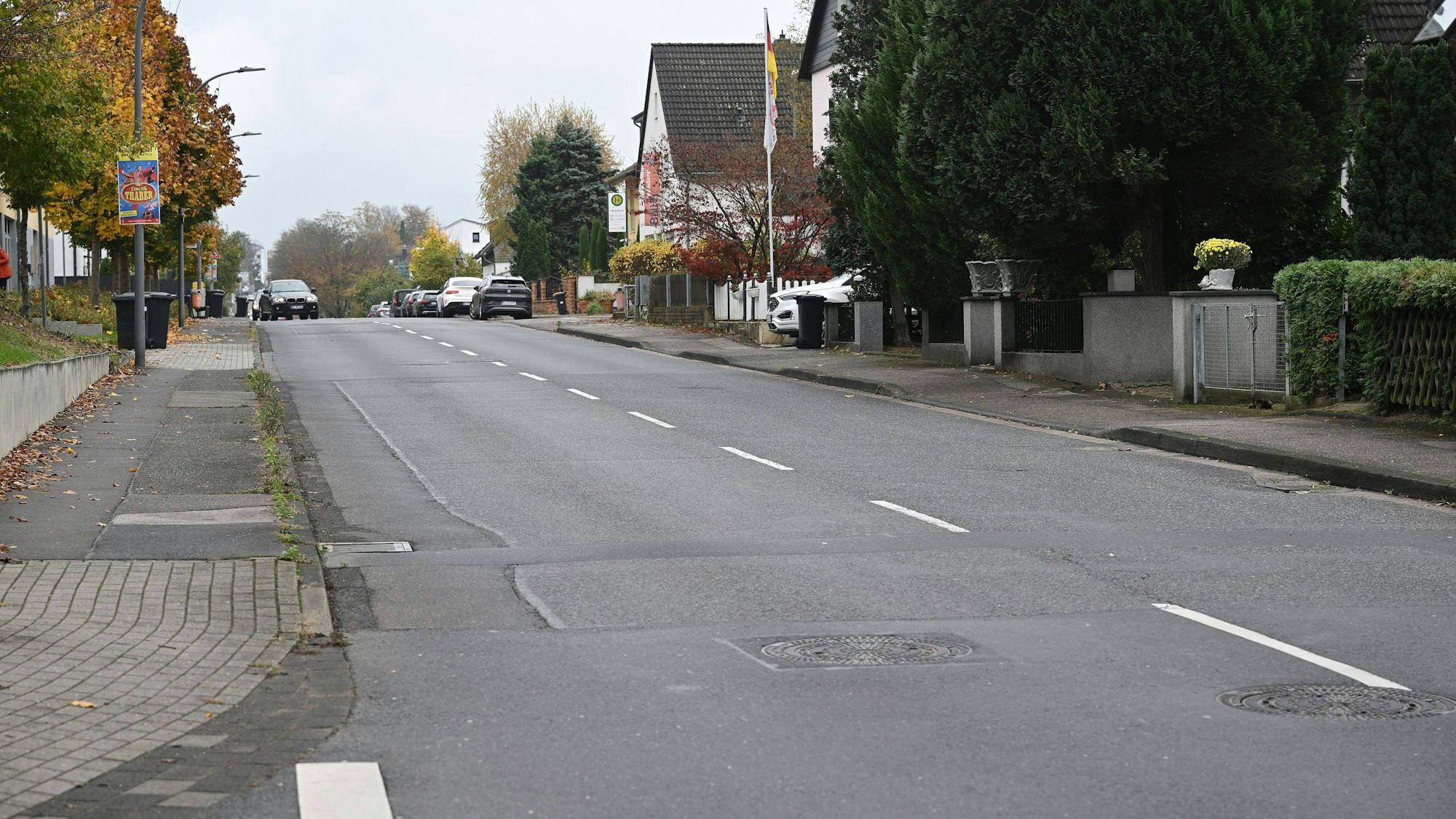 Man sieht den Gehweg sowie die Fahrbahn. Der Belag ist teilweise defekt.