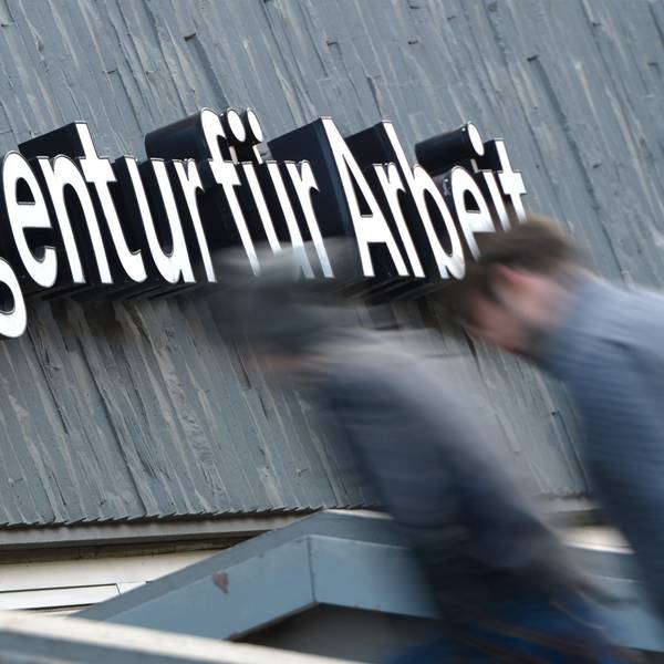 Zwei Männer gehen die Treppe zu einer Arbeitsagentur hinauf.