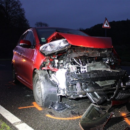 Ein schwer beschädigter roter Kia steht am Heck eines weiteren, ebenfalls beschädigten Fahrzeugs auf der Altenberger-Dom-Straße in Odenthal.