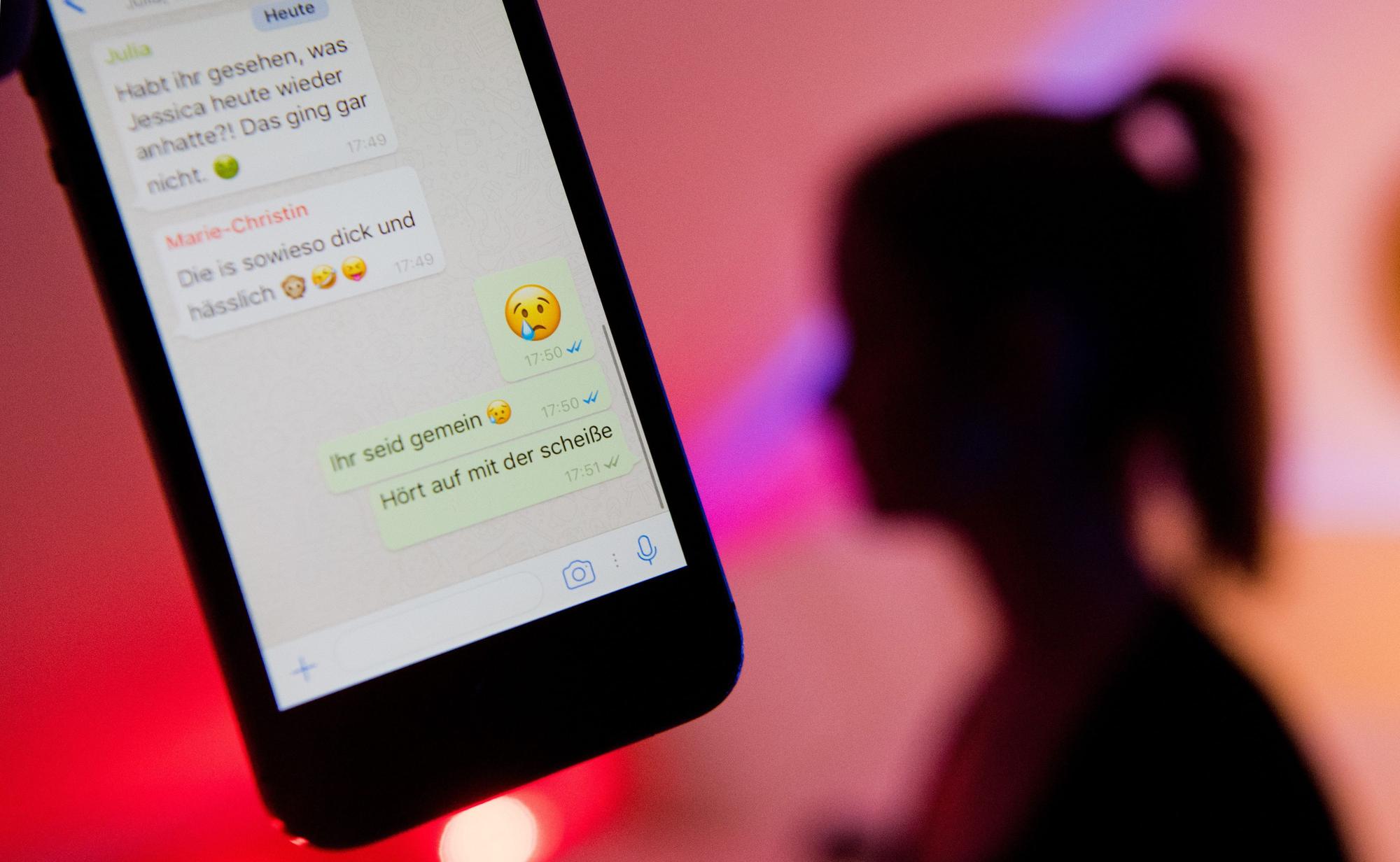 Jugendliche stehen massiv unter dem Eindruck aggressiver, unversöhnlicher Meinungskämpfe und persönlicher Angriffe in den sozialen Medien. Das Symbolbild zeigt Chat-Nachrichten auf einem Handy und die Silhouette eines Mädchens im Hintergrund.