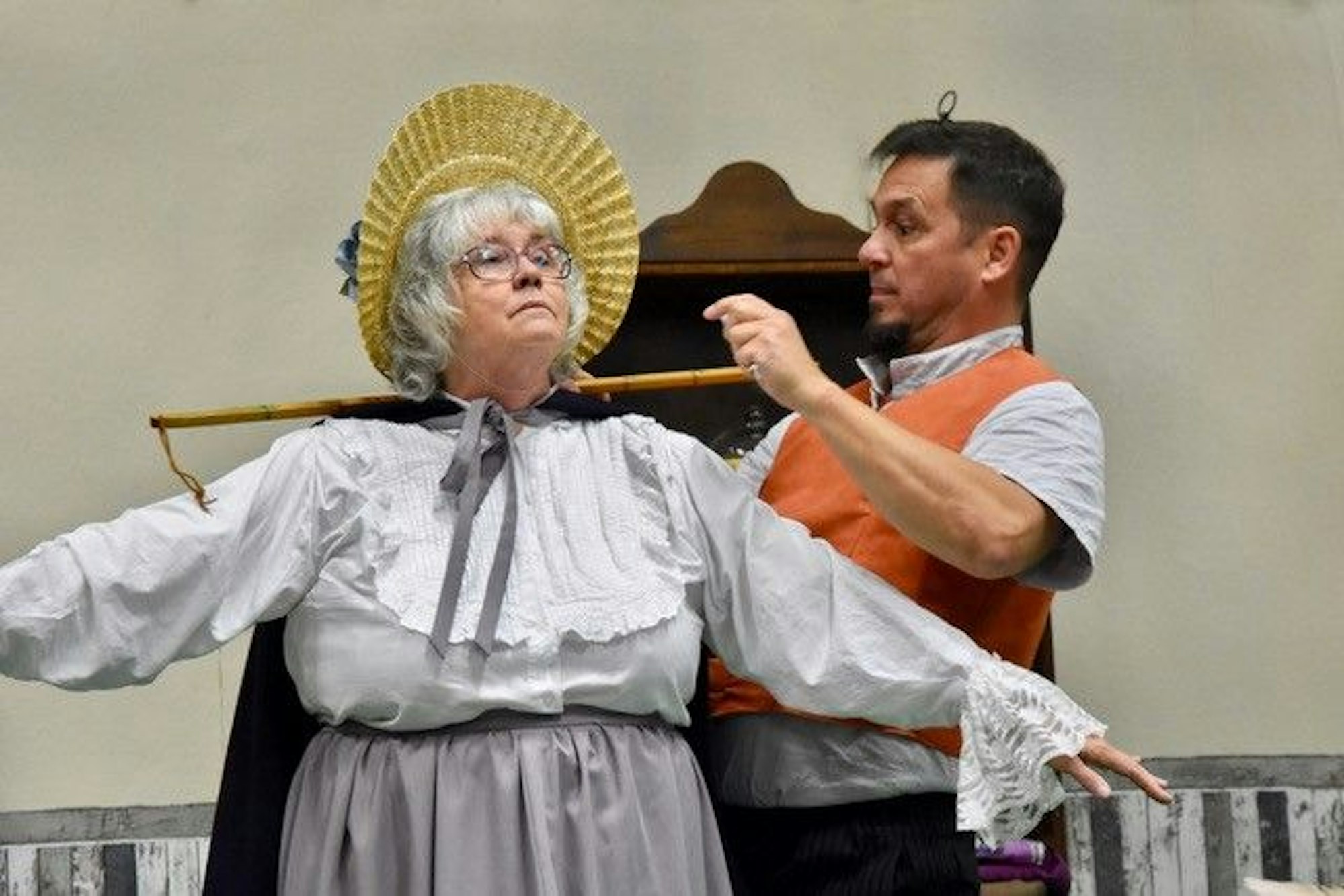 Ein Mann und eine Frau auf einer Theaterbühne. Die Frau trägt ein Biedermeierkostüm.