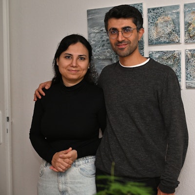 Das Ehepaar steht vor einem abstrakten Bild, das an der Wand hängt.