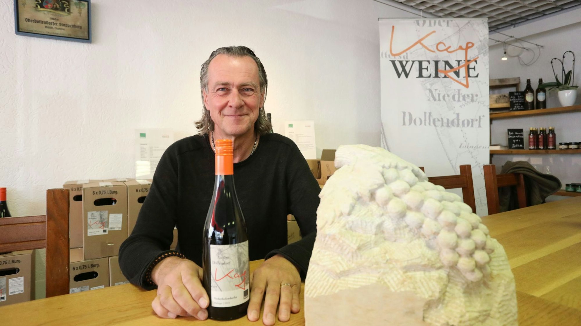 Wein im Siebengebirge, Winzer Kay Thiel zeigt eine Weinflasche.