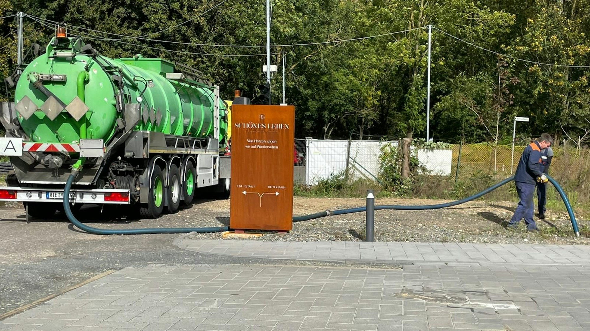 Das Foto zeigt einen Mann, der Abwasser aus einer Zisterne absaugt und einem Tankfahrzeug zuführt.