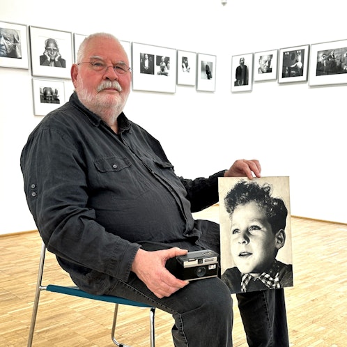 Der Fotograf Gerd van Rijn aus Nümbrecht mit der alten Instamatic und dem Porträtfoto seiner selbst als Junge. In seiner Heimatgemeinde ist ihm nun eine Ausstellung gewidmet.
