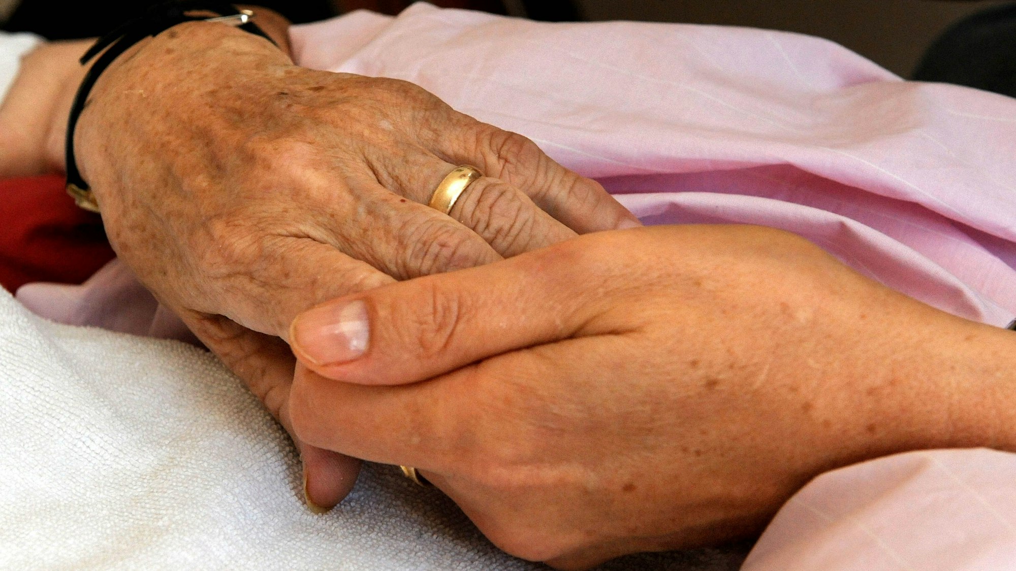 Die Hand einer Frau hält die einer anderen (Symbolfoto).