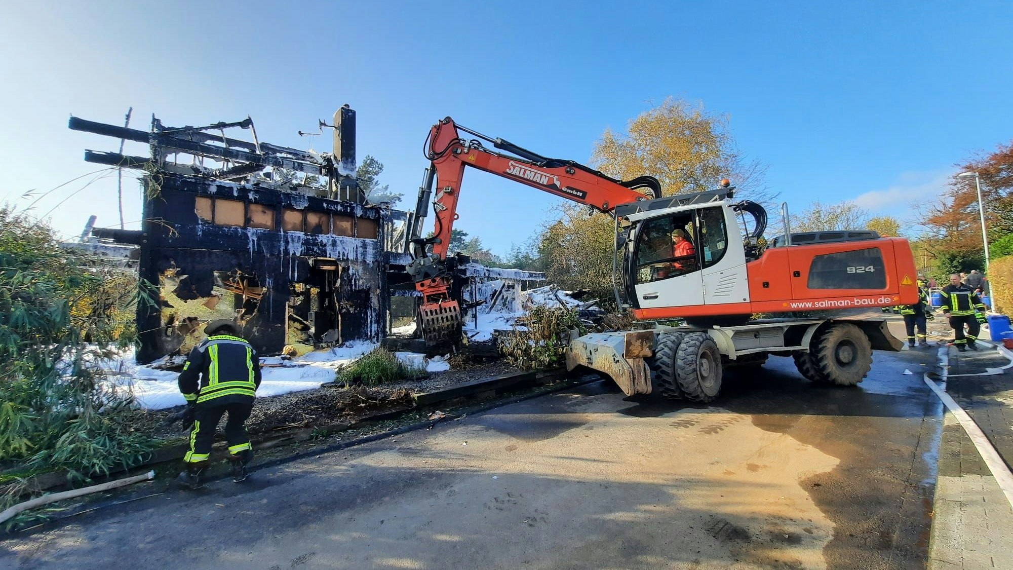 Ein Bagger im Einsatz an einer Brandruine.