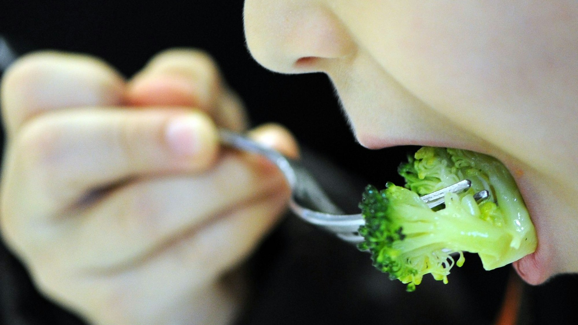 Ein Kind isst Brokkoli.