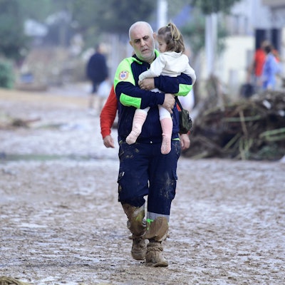 In Paiporta bei Valencia trägt ein Helfer ein Kind aus einem von der Flut zerstörten Bereich.