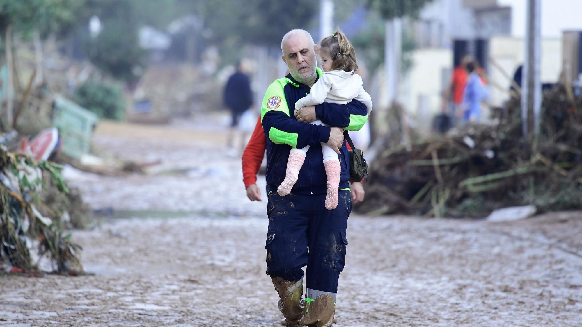 In Paiporta bei Valencia trägt ein Helfer ein Kind aus einem von der Flut zerstörten Bereich.