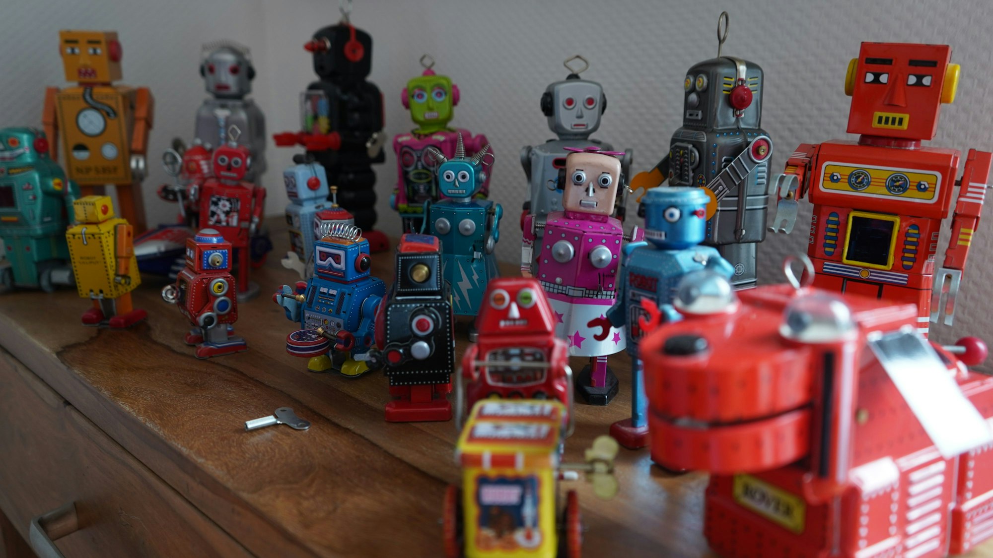 Das Foto zeigt diverse aufziehbare Roboter-Figuren auf einem Schrank.