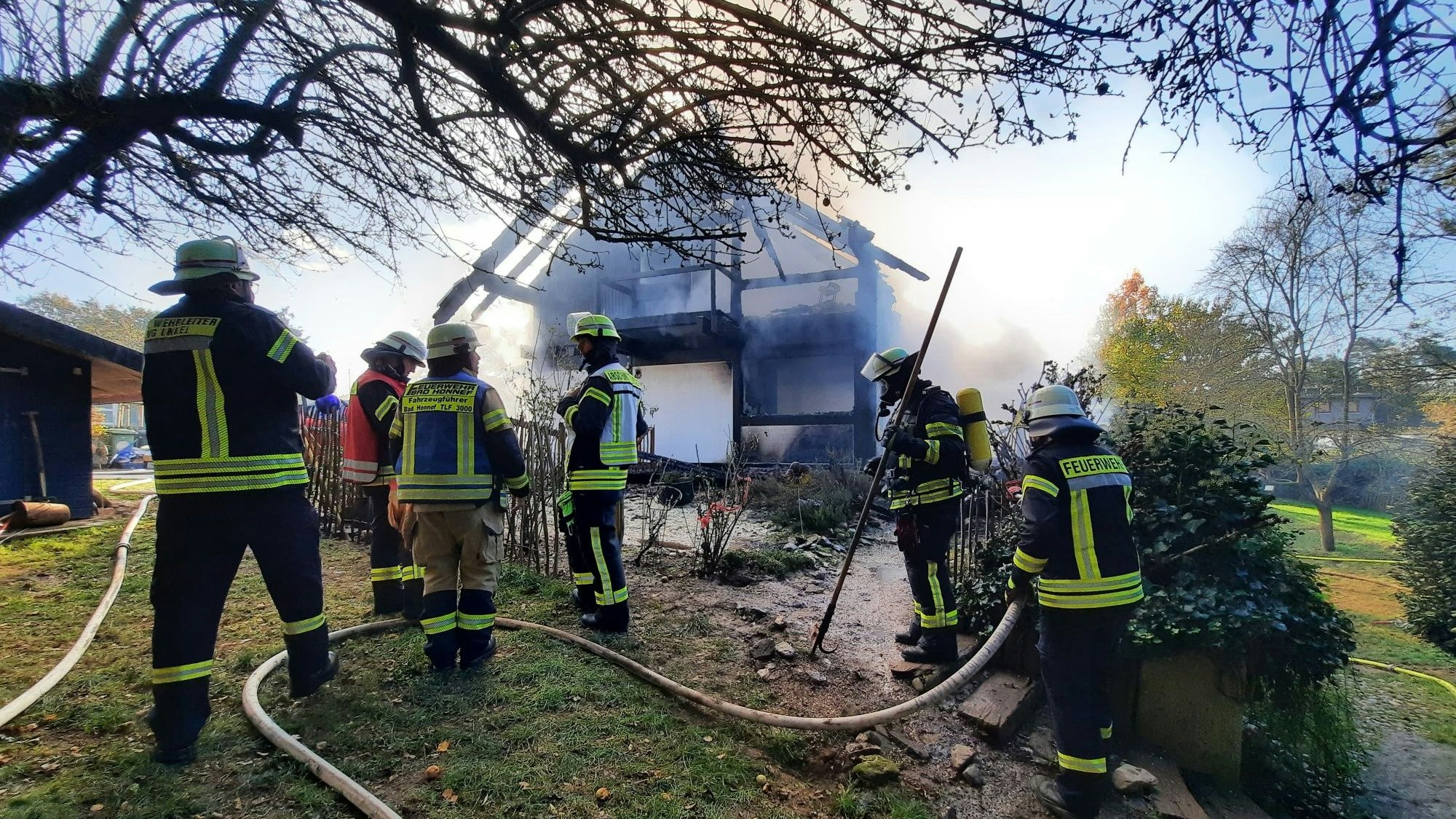 Feuerwehrleute im Einsatz neben dem qualmenden Gebäude.
