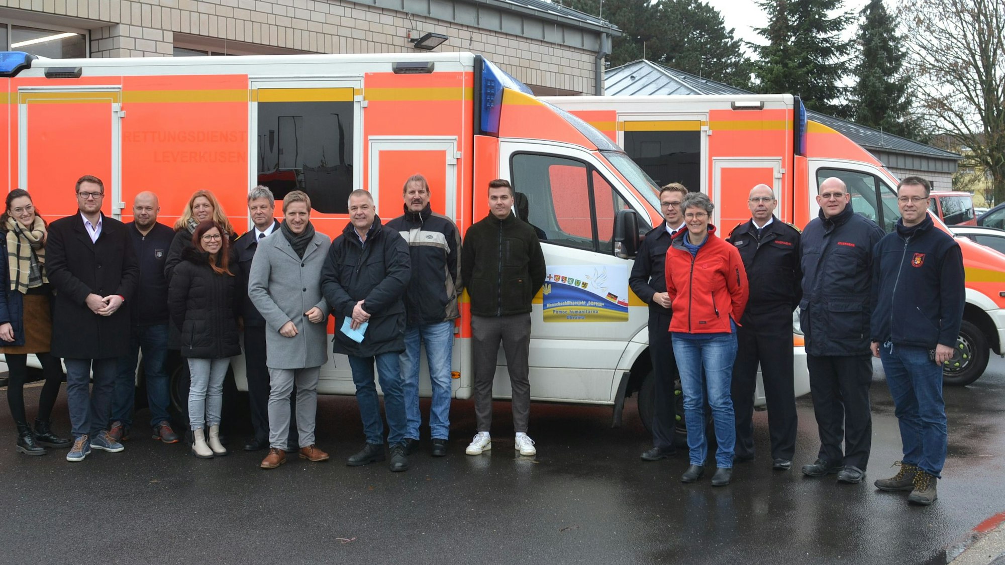 Auf dem Bild sind zwei Rettungswagen und eine Gruppe von ehrenamtlichen Helfern zu sehen.